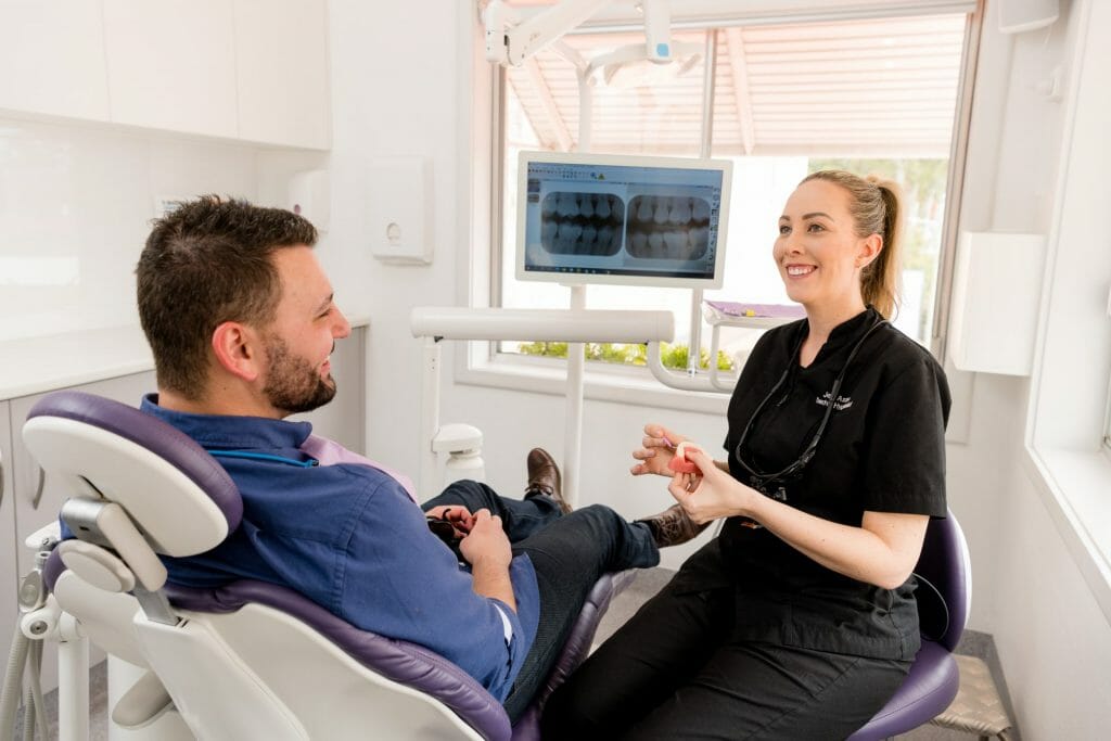 Jennifer Aston smiling at a patient in a dental chair