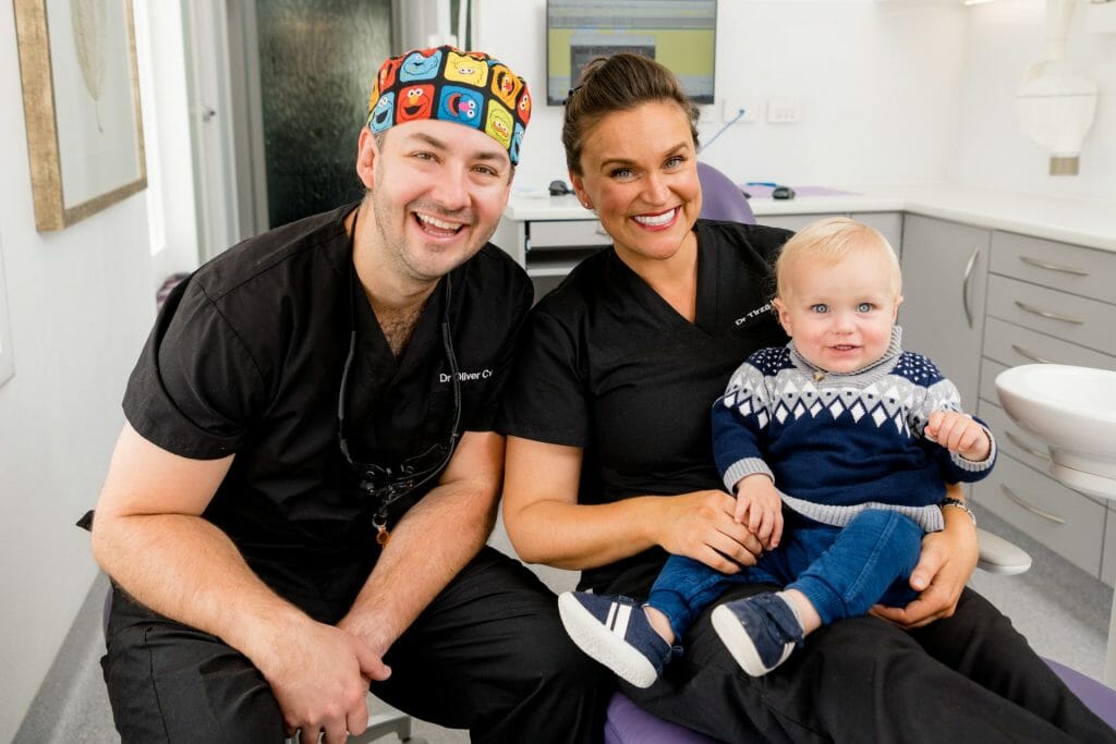 Dr Oliver Cvekus and Dr Tirza Harley sitting with a young child and smiling at the camera