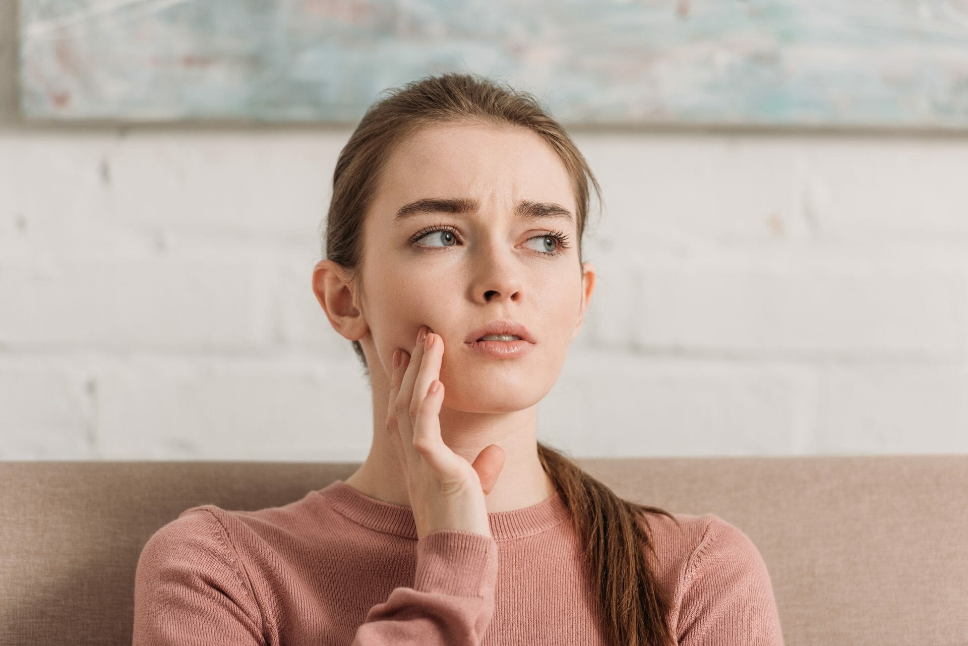 A girl holding her cheek and looking concerned