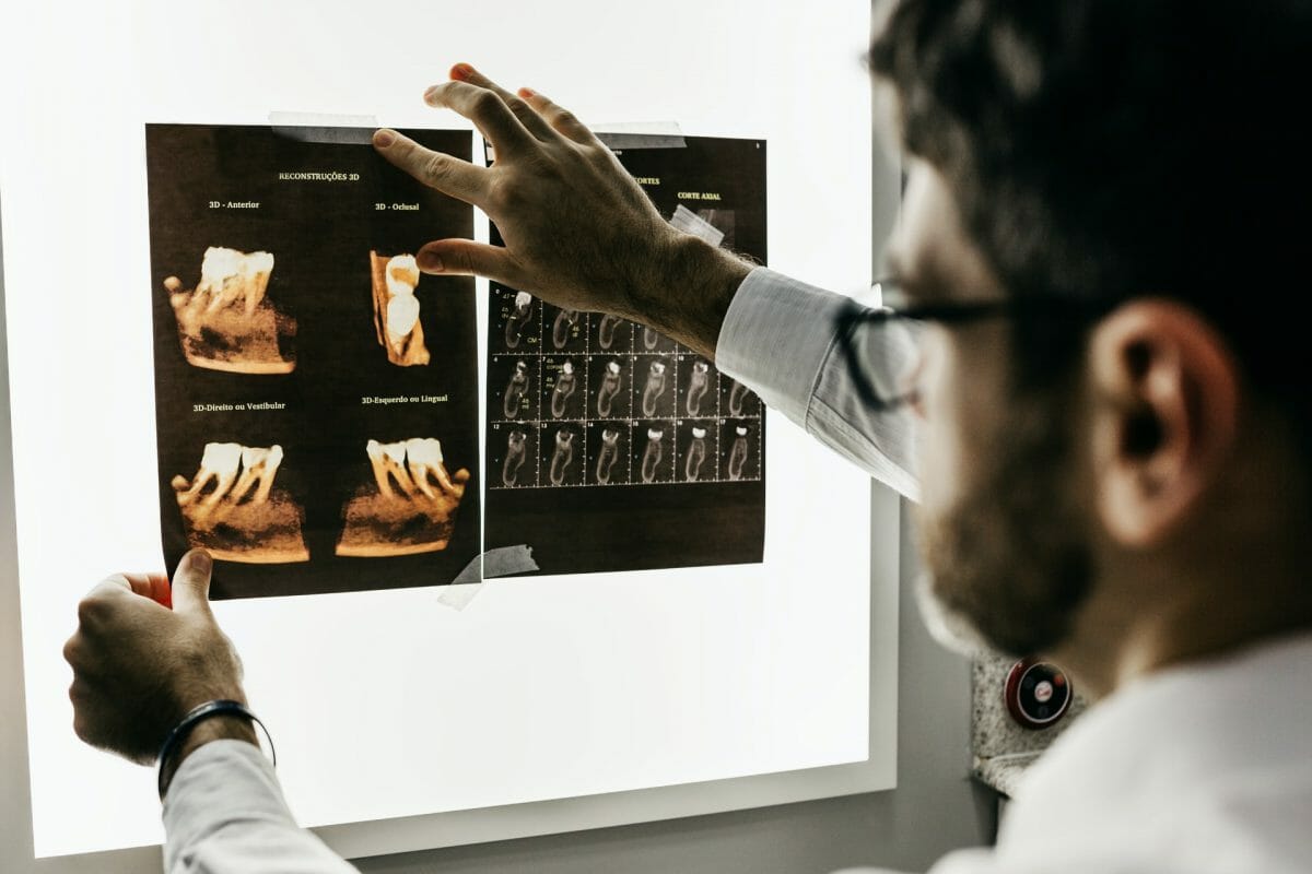 A man looking at tooth x-rays on a backlit monitor