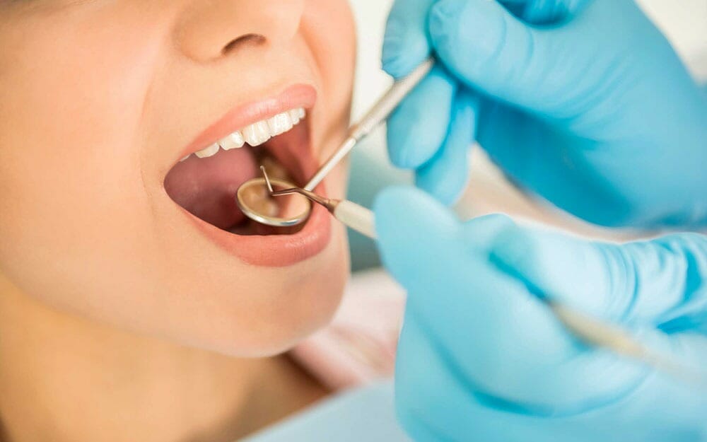 A close up of a dentist checking a patient's teeth