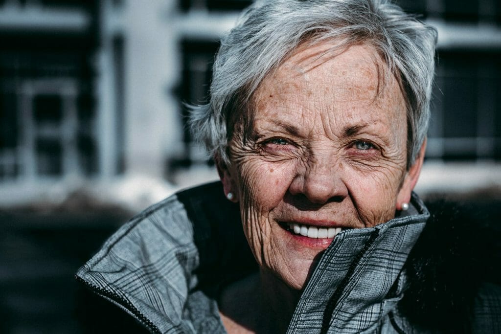 A senior woman wearing a jacket and smiling